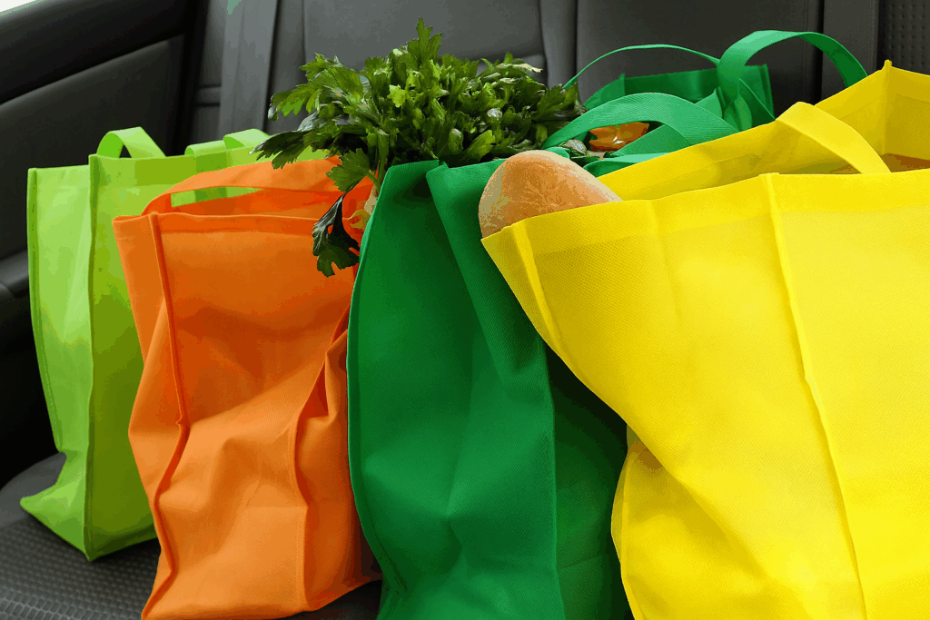 有4個顏色鮮豔的客製環保袋,裝著食物擺放在汽車後座上